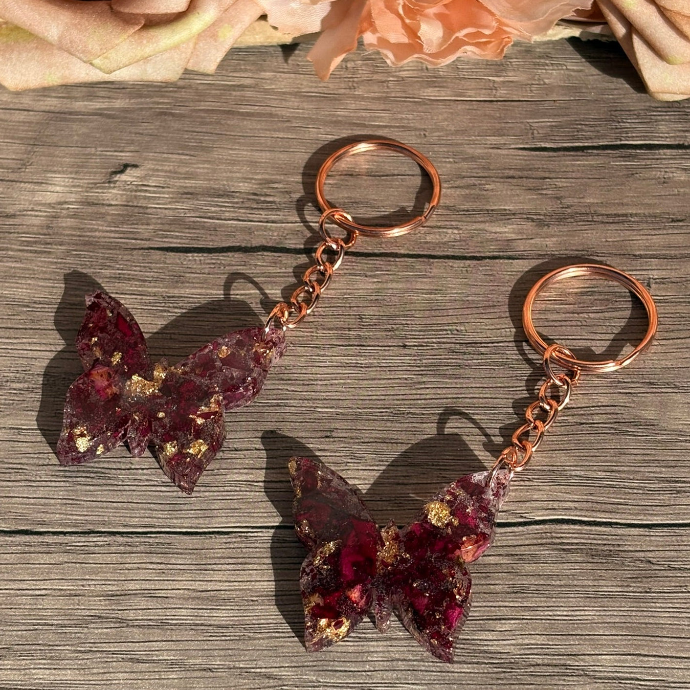 Handgefertigte Schlüsselanhänger in Schmetterlingsform aus Epoxidharz mit echten Rosenblättern und Blattgold